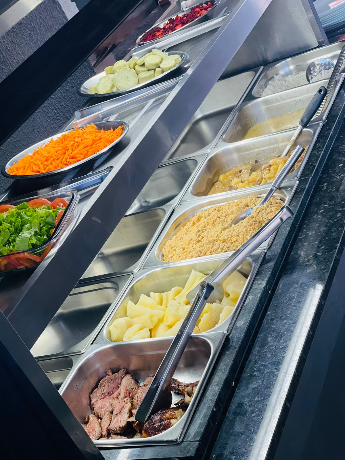 Buffet de almoço com saladas, acompanhamentos e churrasco